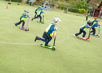 Kids Riding On Scooters In Playground